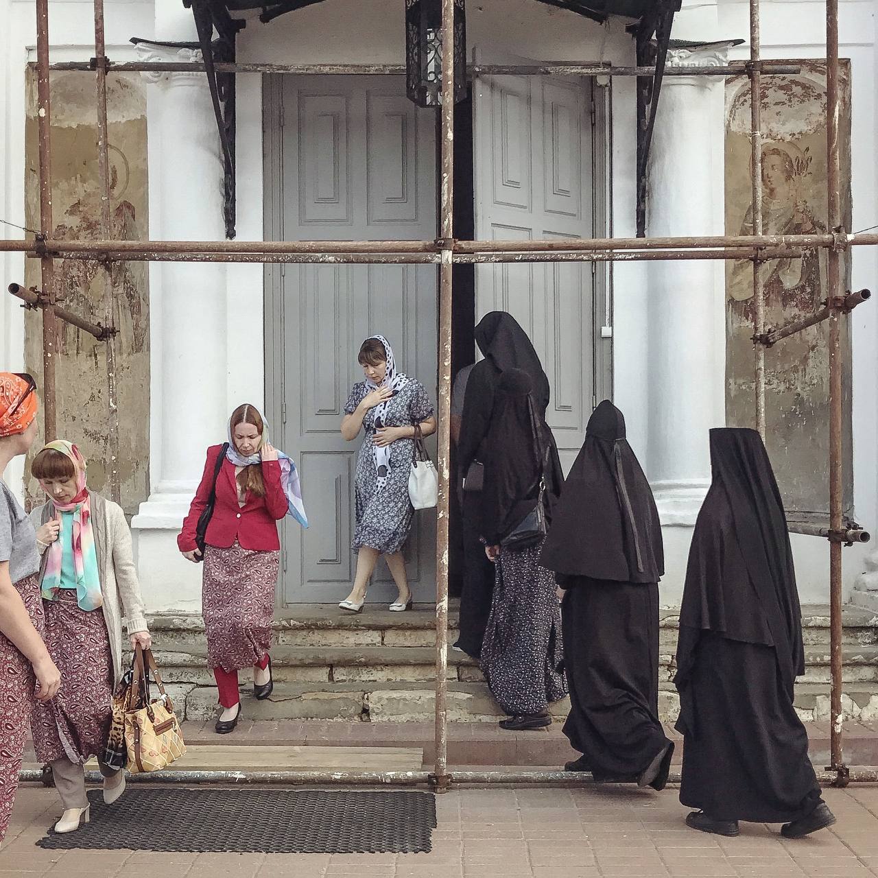 A group of nuns enters a church and a group of women leaves it