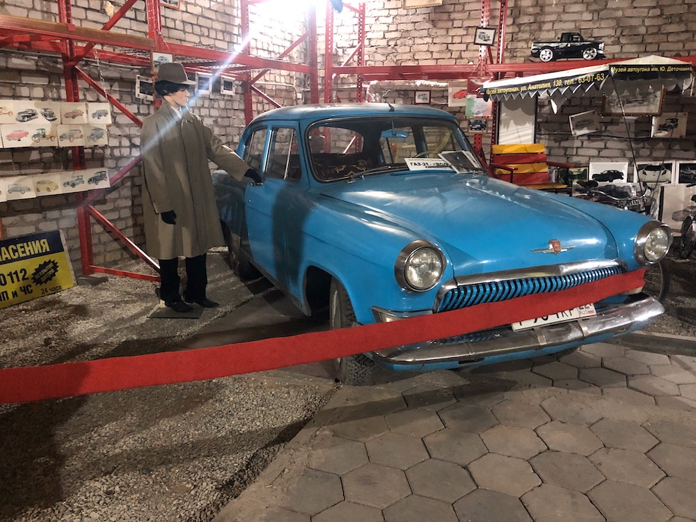 A bright blue antique car and its mannequin assailant. 