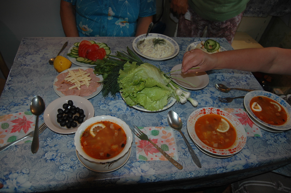 A table full of fresh vegetables, salads, and soups, 