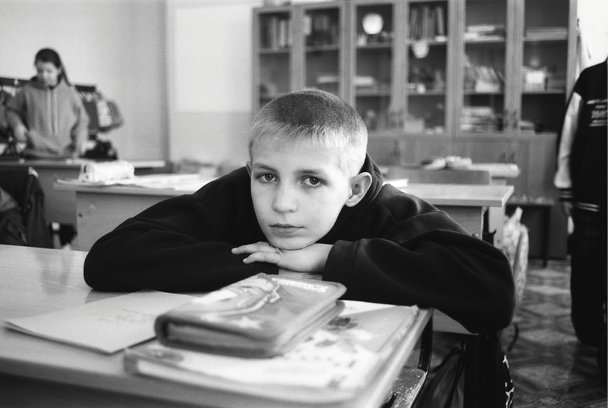 Child at school desk, looking at camera.