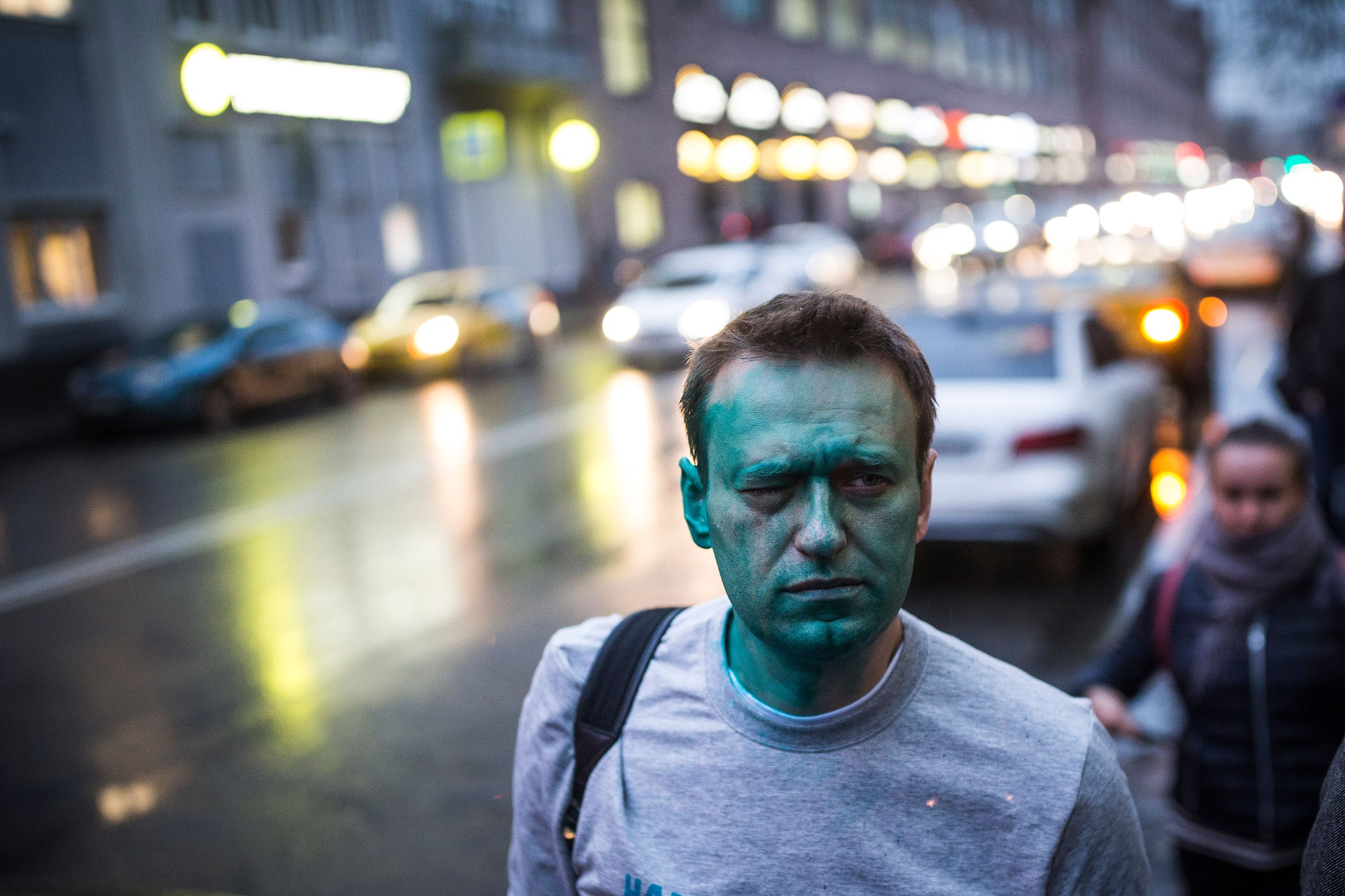 A very green-faced Navalny stands in the street.