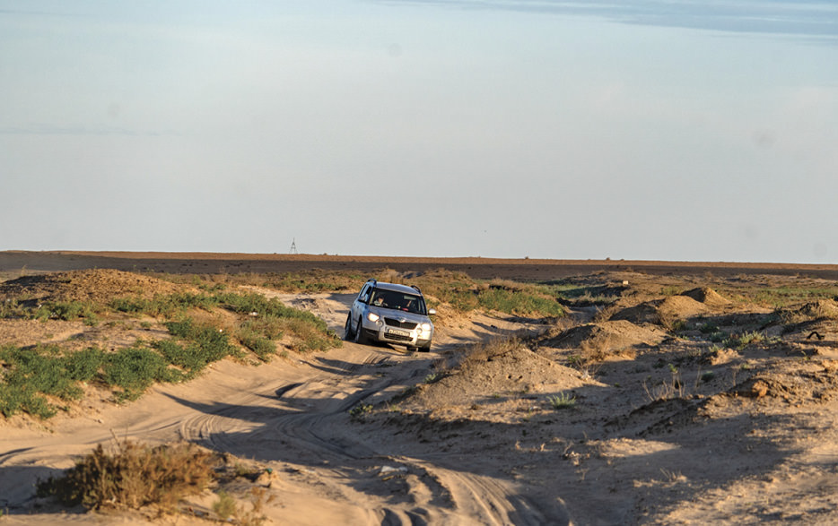 Car driving across sand dunes