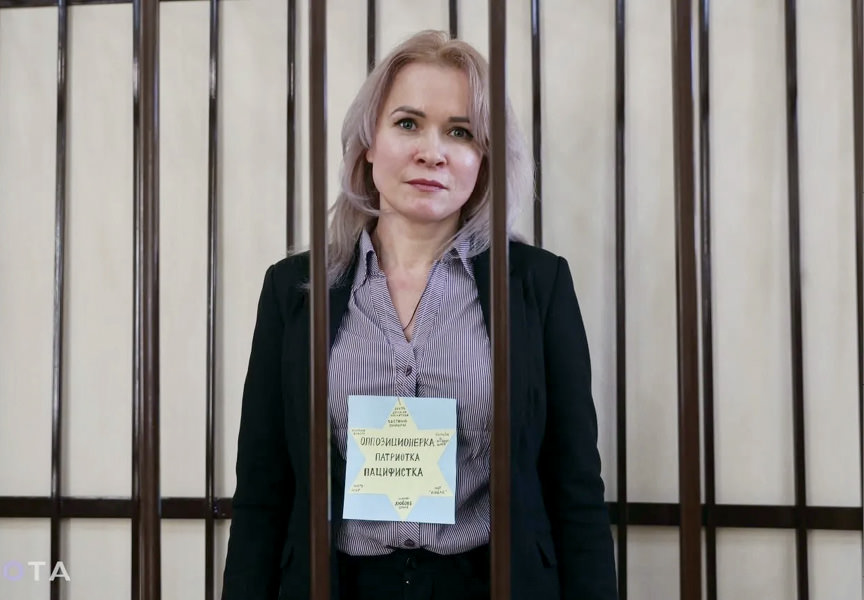 Woman standing in jail cell.