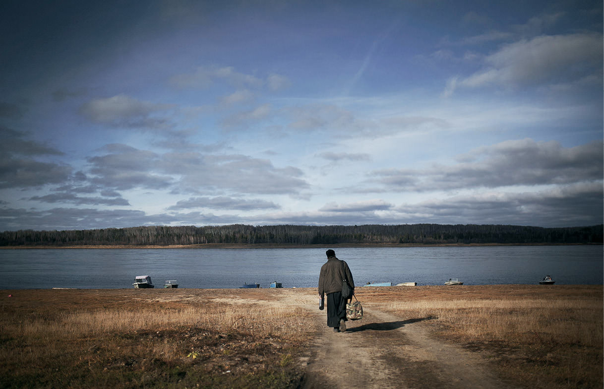 Priest walking toward shoreline.
