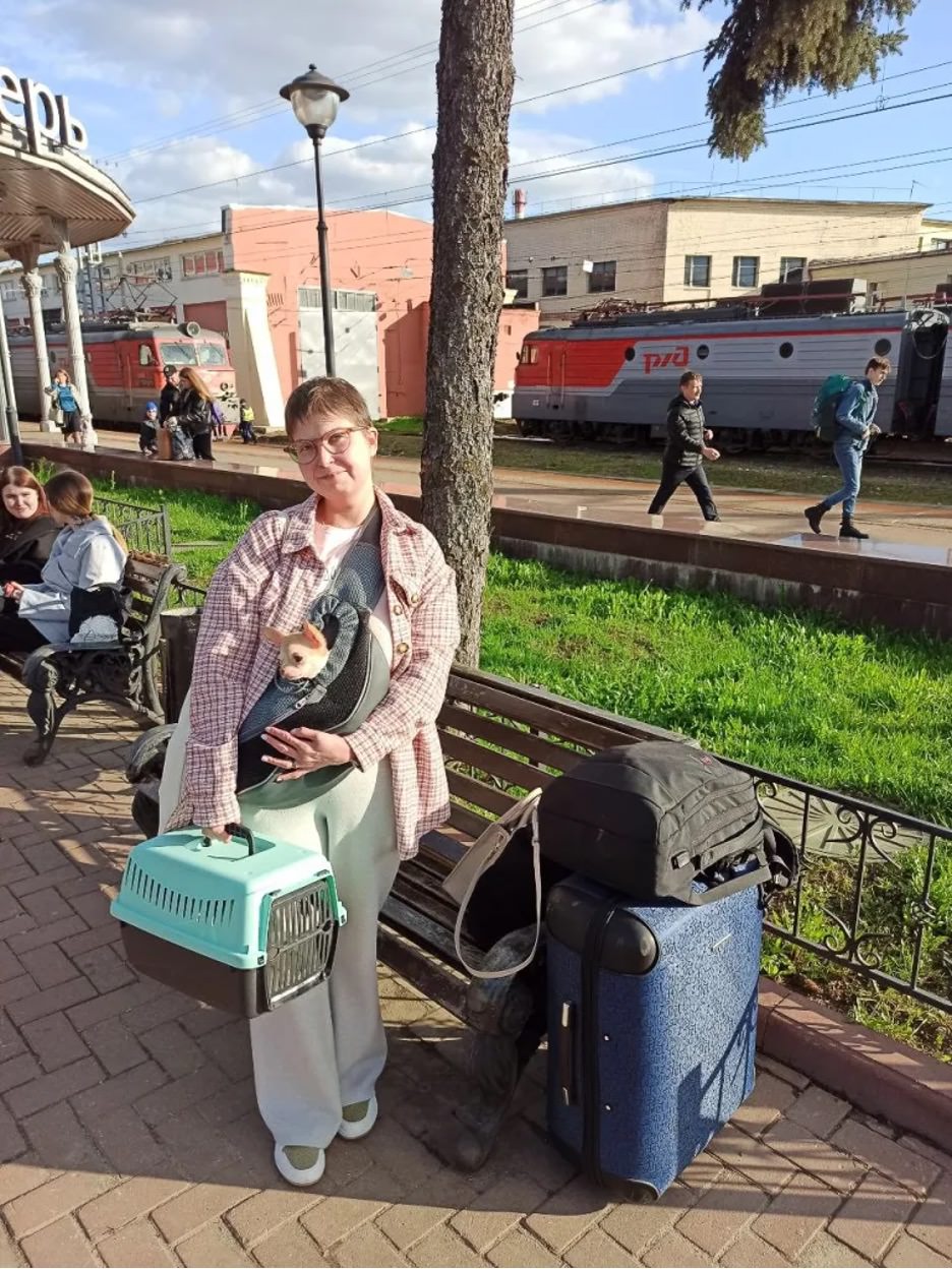 Woman holding dog carrier and looking at camera.