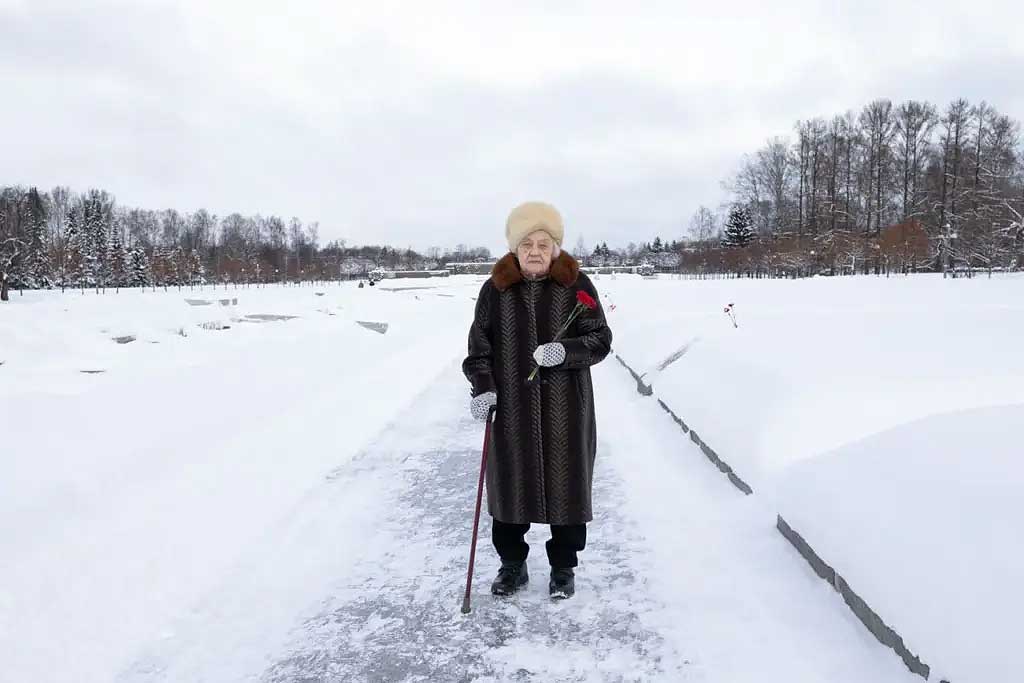 Woman and frozen cemetery holding a carnation.