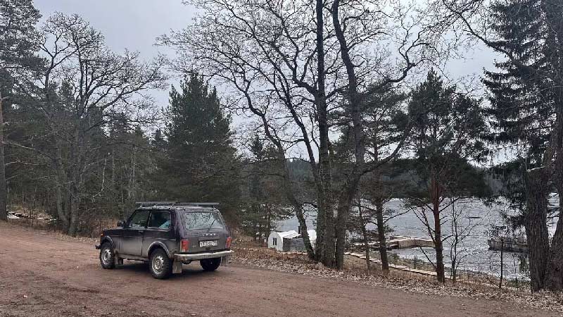Car parked by a road by a lake.