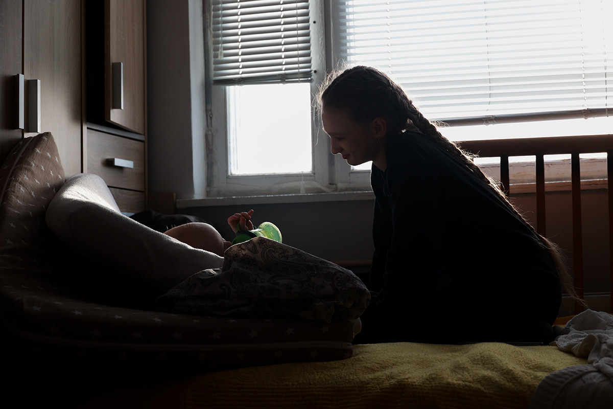 Young girl tends to infant child.