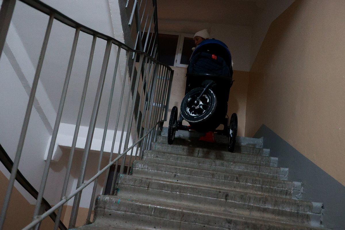 Woman dragging stroller up stairs.
