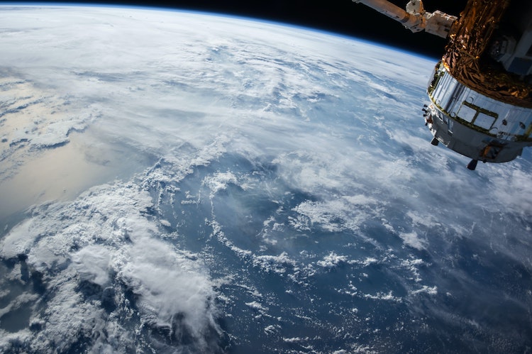 A satellite floats high above the blue earth. 